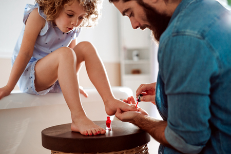 Young father painting small daughters nails in a bathroom at home.の写真素材