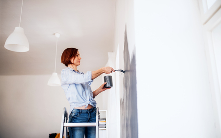 A portrait of young woman painting wall black. A startup of small business.の写真素材