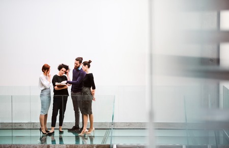 Group of young businesspeople standing near staircase, talking.の写真素材