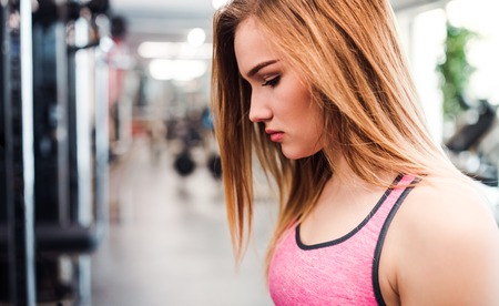 A portrait of young sad girl or woman in a gym. Copy space.