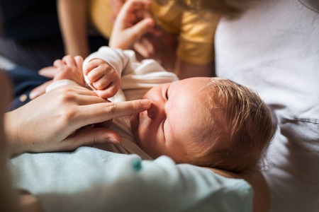 Midsection of parents with newborn baby and small toddler son at home.の写真素材