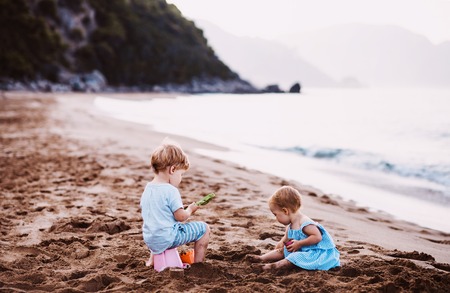 Two toddler children playing on sand beach on summer holiday.の写真素材
