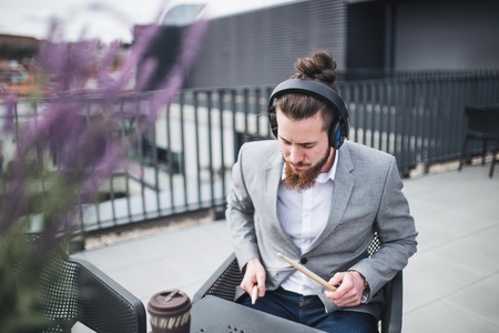 A young businessman with headphones sitting on a terrace, having fun.