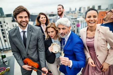 A group of joyful businesspeople having a party outdoors on roof terrace in city.の写真素材