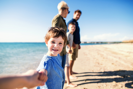 Young family with two small children standing outdoors on beach.の写真素材