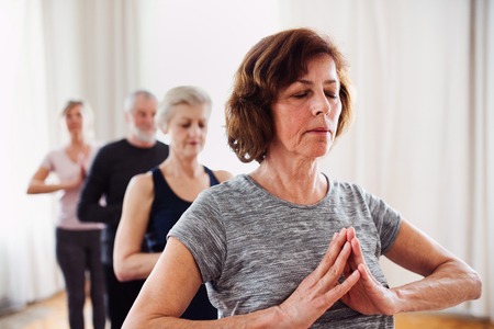 Group of senior people doing yoga exercise in community center club.の写真素材