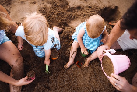 Midsection of family with toddler children playing on beach on summer holiday.の写真素材