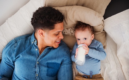 A top view of father and a son indoors at home, drinking milk from bottle.の写真素材