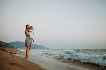 Young mother with a toddler girl on beach on summer holiday.の写真素材