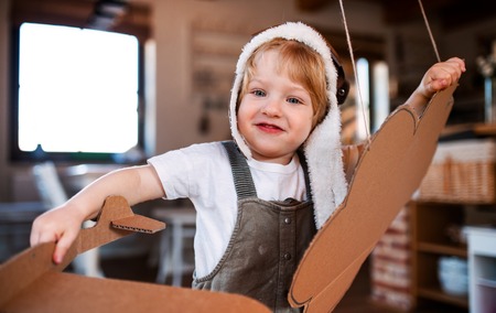 A toddler boy with carton plane playing indoors at home, flying concept.の写真素材