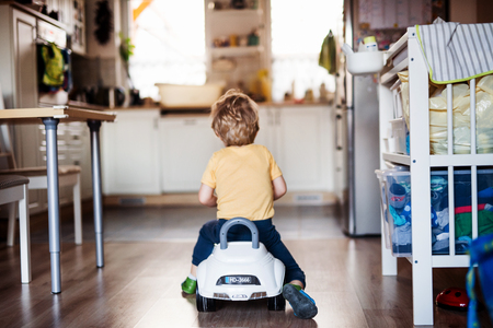 A rear view of a toddler boy with toy car playing at home.の写真素材