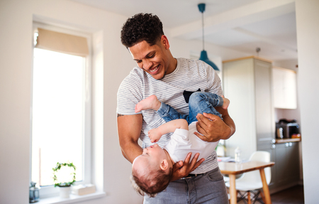 A portrait of father and small toddler son indoors at home, playing.の写真素材