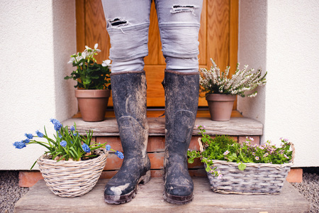 A midsection of young man gardener standing in front of door at home.の写真素材