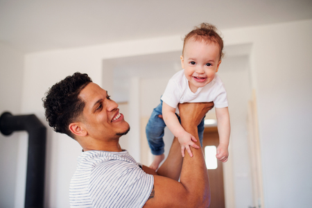 A portrait of father and small toddler son indoors at home, playing.の写真素材
