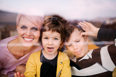 A portrait of young woman with two children at home, looking at camera.の写真素材
