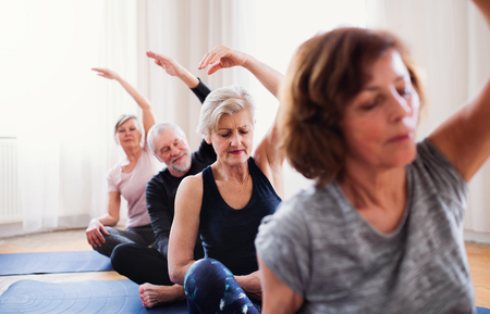 Group of senior people doing yoga exercise in community center club.の写真素材