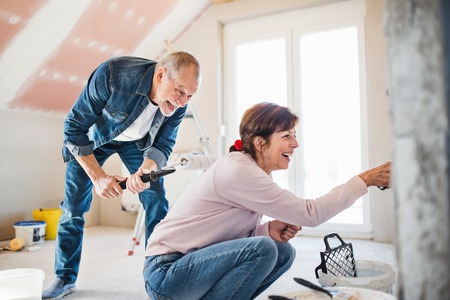 Senior couple painting walls in new home, relocation concept.の写真素材