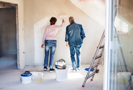 Rear view of senior couple painting walls in new home, relocation concept.の写真素材