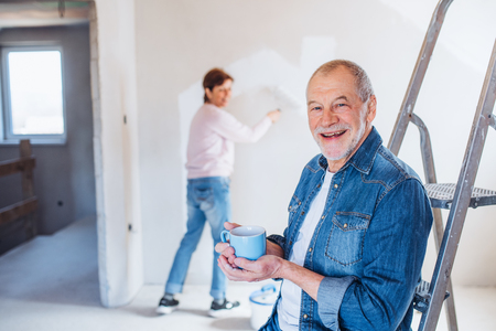 Senior couple painting walls in new home, relocation concept.の写真素材