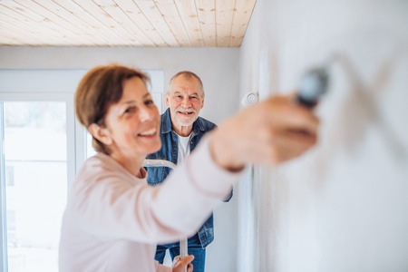 Senior couple painting walls in new home, relocation concept.の写真素材