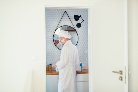 A senior man doing morning routine in bathroom indoors at home. Copy space.の写真素材