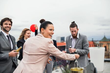 A group of joyful businesspeople having a party outdoors on roof terrace in city.の写真素材