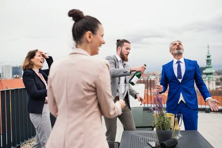 A group of joyful businesspeople having a party outdoors on roof terrace in city.の写真素材