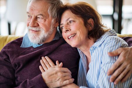 An affectionate senior couple in love sitting on sofa indoors at home.の写真素材