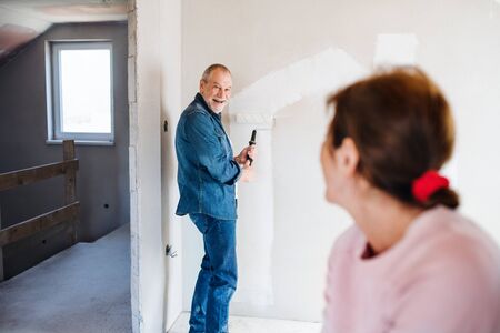 Senior couple painting walls in new home, relocation concept.の写真素材