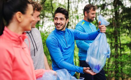 Group of fit people picking up litter in nature, a plogging concept.の写真素材
