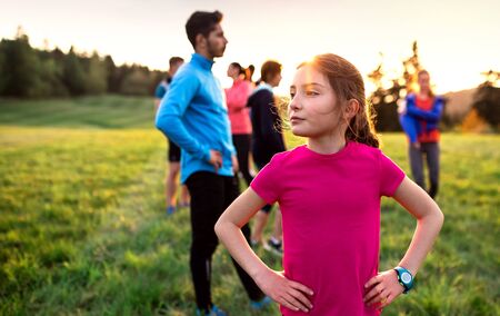 A portrait of small girl with large group of people doing exercise in nature.の写真素材