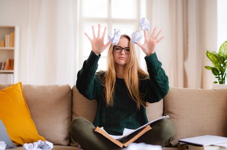 An unhappy female student sitting on sofa, studying.