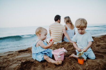 Toddler children with parents playing on sand beach on summer holiday.の写真素材