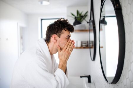 Young man washing face in the bathroom in the morning, daily routine.の写真素材