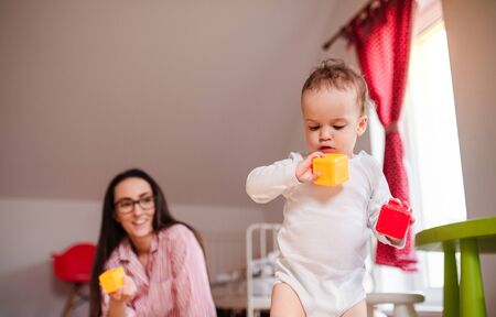 Young mother with small toddler son indoors at home, playing.の写真素材