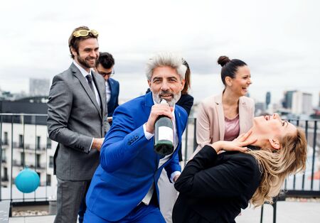 A group of joyful businesspeople having a party outdoors on roof terrace in city.の写真素材