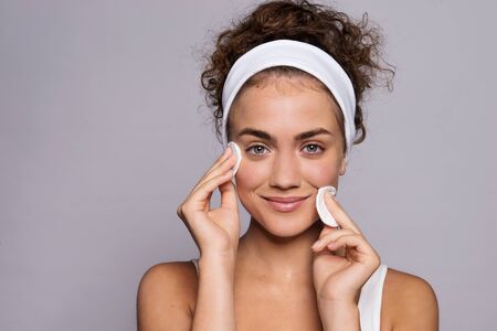 Portrait of a young woman cleaning face in a studio, beauty and skin care.の写真素材