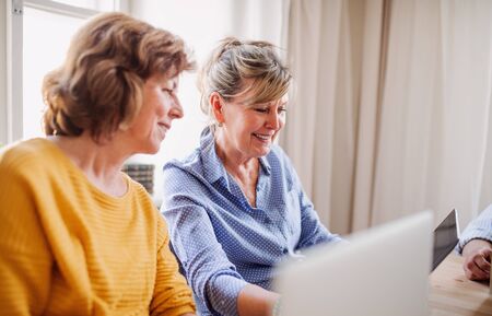Senior women using laptops and tablets in community center club.