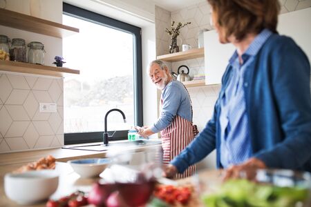 A portrait of senior couple indoors at home, cooking.の写真素材