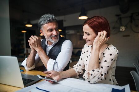 Man and woman having business meeting in a cafe, using smartphone.の写真素材