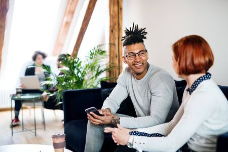 Group of young businesspeople talking in office, start-up concept.
