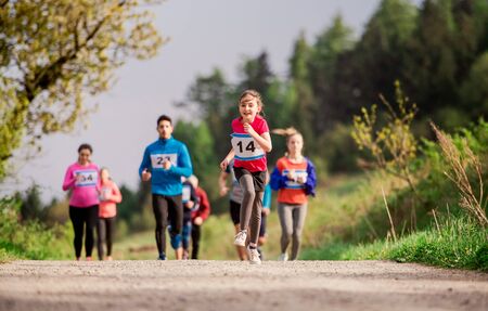 Large group of multi generation people running a race competition in nature.