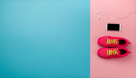 A studio shot of running shoes and smartphone on color background. Flat lay.
