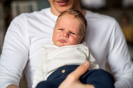 A young father with a newborn baby son at home, a midsection.