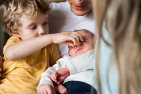 Young parents with newborn baby and small toddler son at home, a close-up.の写真素材