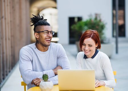 Young businesspeople with laptop in courtyard, start-up concept.