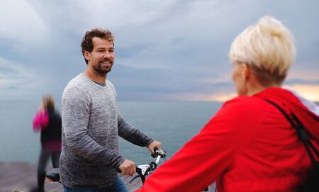 Couple with bicycles outdoors on beach, talking.
