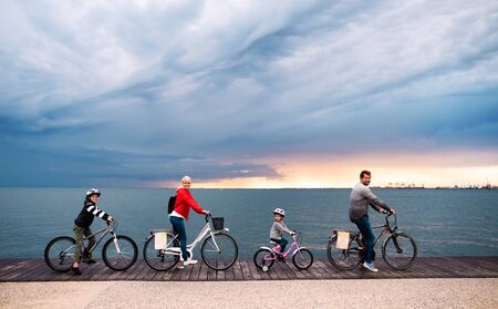 Young family with small children and bicycles outdoors on beach.
