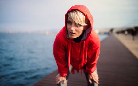 Front view portrait of young sportswoman standing outdoors on beach.