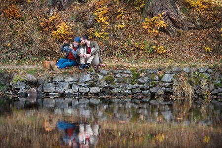 Senior father and his son with binoculars and picnic basket in nature.の写真素材